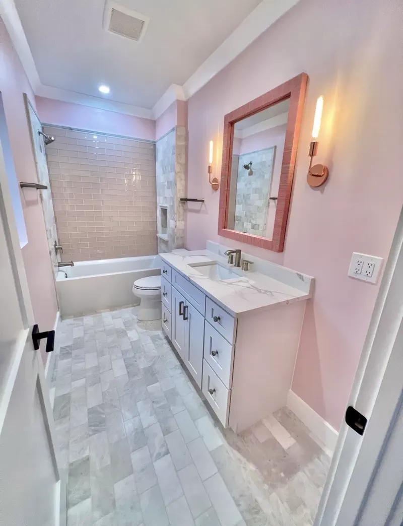 Bathroom with blush walls, white shaker vanity, rose-gold sconces and mauve subway tub surround