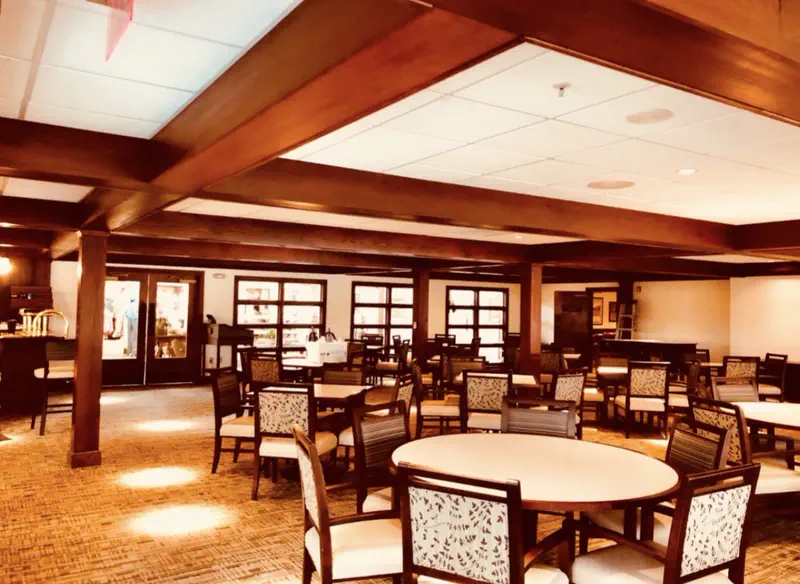 Commercial dining hall with wood-beam ceiling, dining tables and a bar