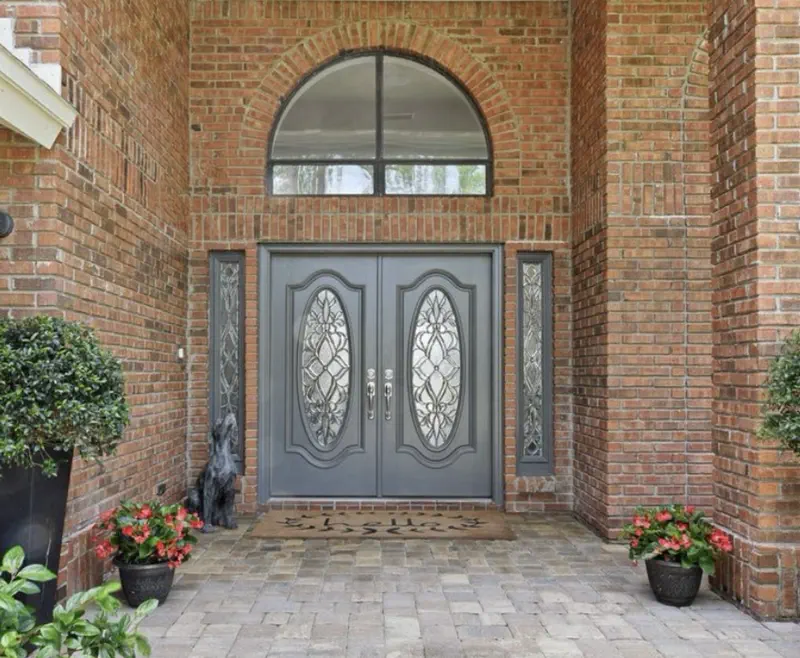 Brick front entry remodel before — red brick archway with ornate gray oval-glass double doors by All Beaches Remodeling and Repair