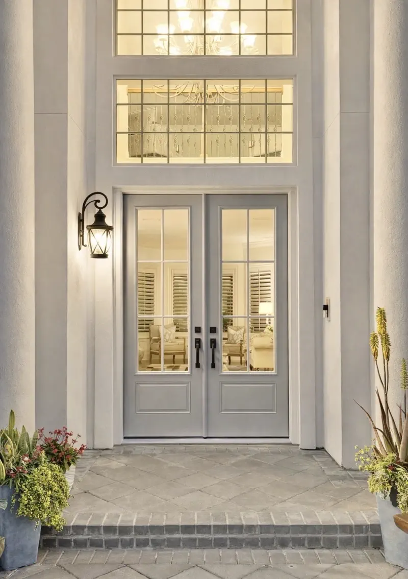 Front entry with gray six-pane glass double doors, lantern sconce and planters
