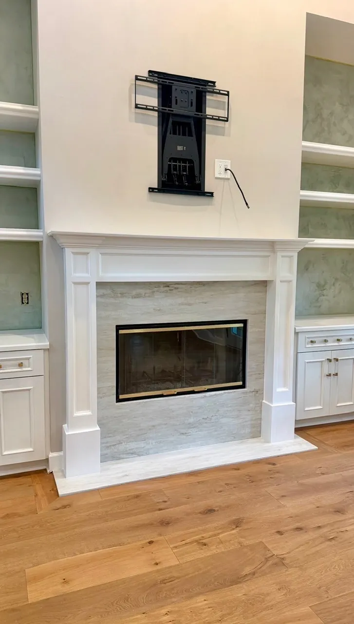 Living room fireplace remodel after — wide-plank wood floors and a refinished fireplace surround by All Beaches Remodeling and Repair