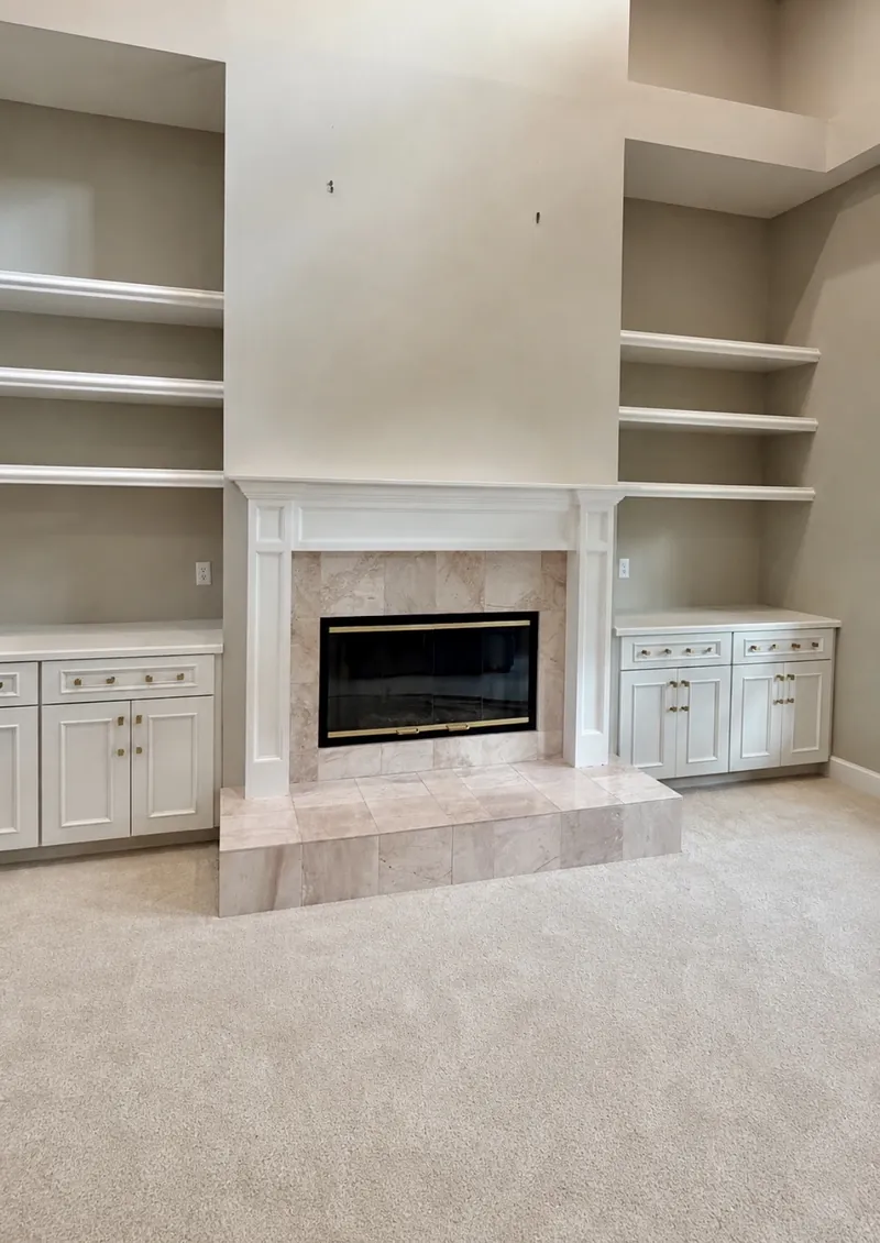 Living room fireplace remodel before — carpeted room with an older beige-tile fireplace and empty shelves by All Beaches Remodeling and Repair