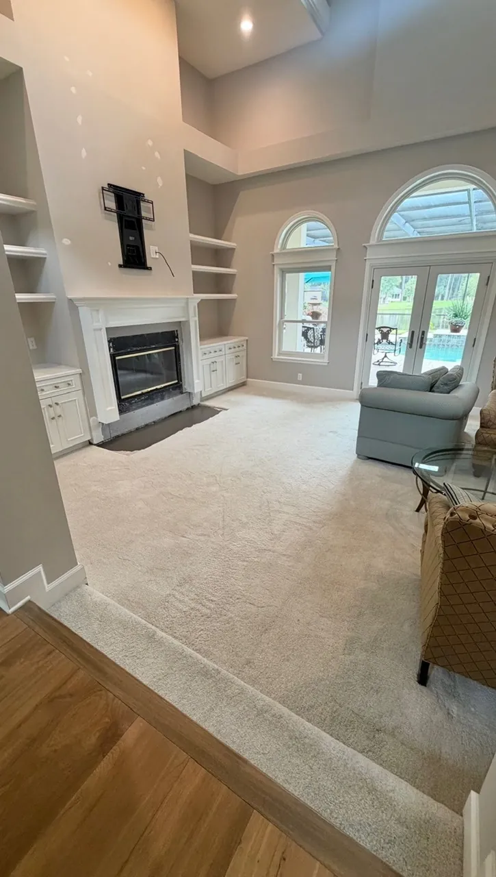 Living room remodel before — carpeted room with empty fireplace shelves and arched patio doors by All Beaches Remodeling and Repair