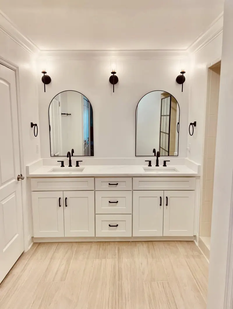 Completed master bathroom with a custom double vanity, quartz countertop, arched mirrors and tile flooring in Northeast Florida