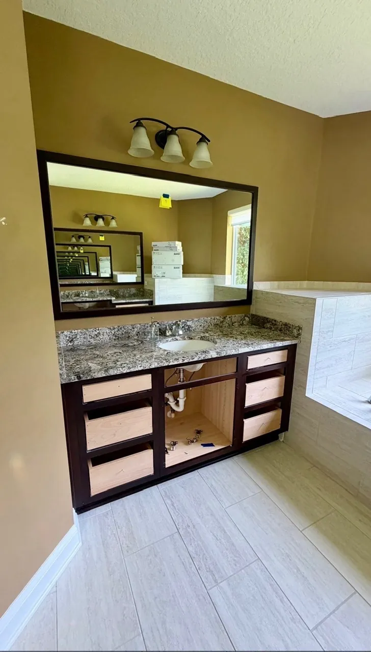 Master bathroom vanity remodel before — dark brown full-width vanity with drawers pulled out and plumbing exposed by All Beaches Remodeling and Repair