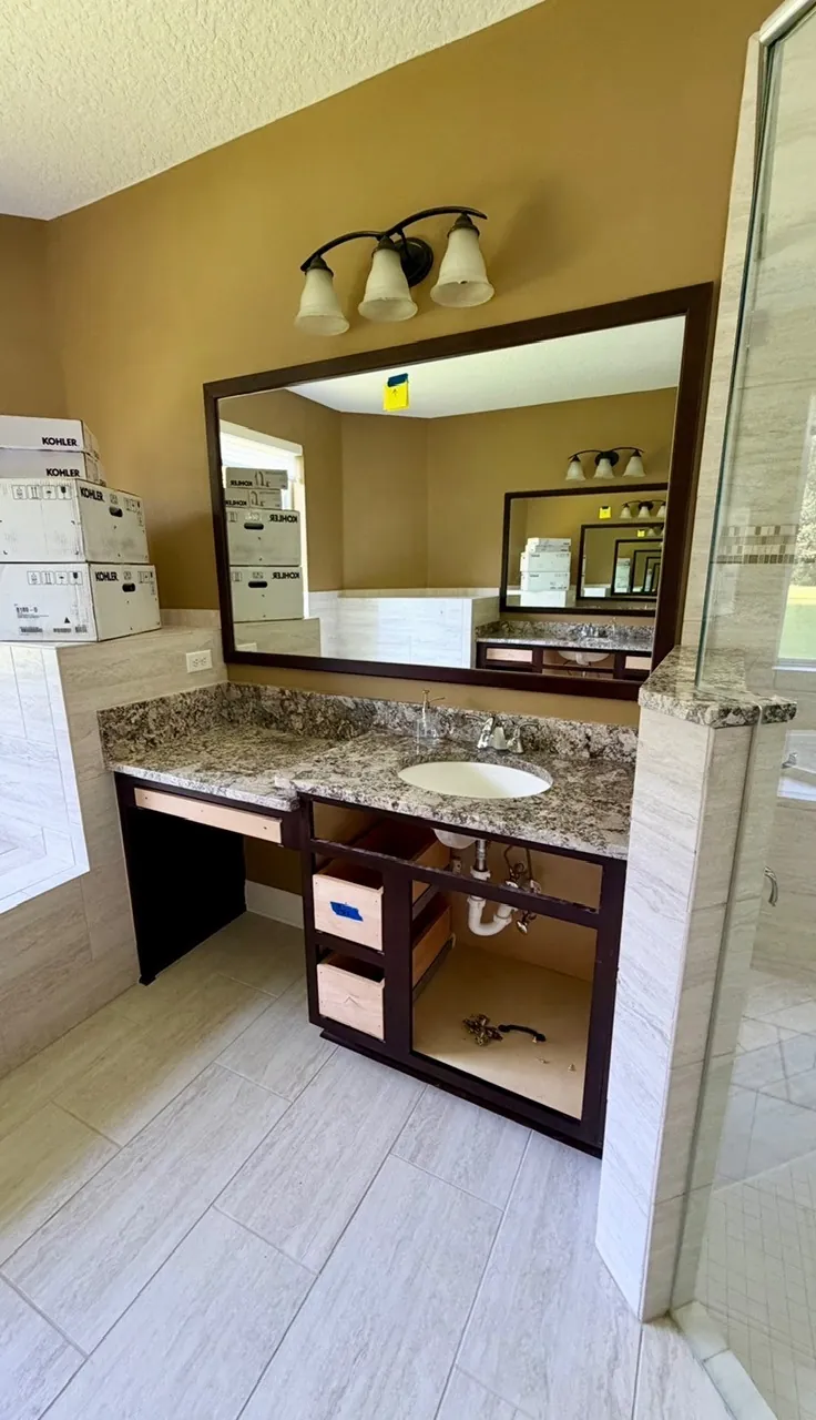 Master bathroom vanity remodel before — dark brown makeup-desk vanity mid-renovation with Kohler boxes and drawers removed by All Beaches Remodeling and Repair
