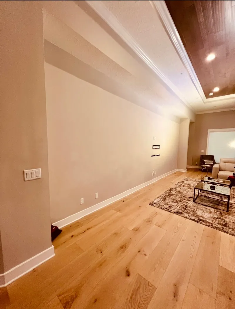 Media wall remodel before — bare beige wall with an exposed TV mount and outlets by All Beaches Remodeling and Repair