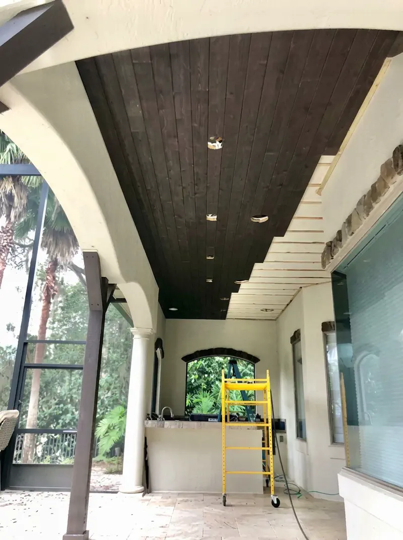 Finished tongue-and-groove stained wood porch ceiling with recessed lighting on a Northeast Florida lanai