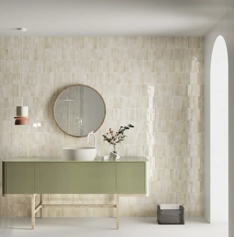 Powder room with sage floating vanity, cream vertical subway tile and a circular mirror