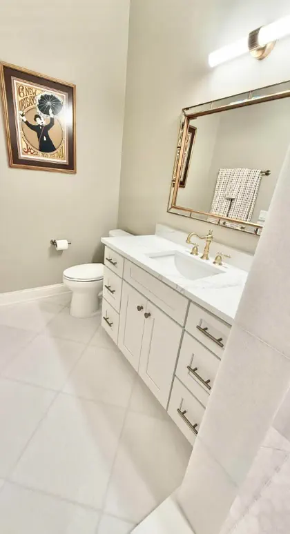 Bathroom with white shaker vanity, gold faucet and hardware, gold-framed mirror and diagonal tile